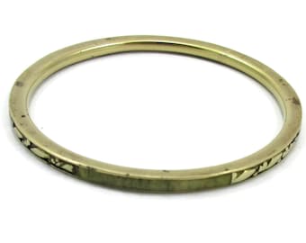 May include: A gold-colored bangle bracelet with a simple design. The bracelet has a smooth, rounded exterior with a subtle, decorative pattern along the edge. The overall aesthetic is minimalist and elegant, suitable for everyday wear.