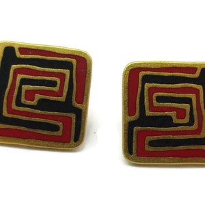 Puede incluir: Un par de pendientes cuadrados con un borde dorado. Los pendientes presentan un dise&ntilde;o laber&iacute;ntico rojo y negro. Los pendientes est&aacute;n sobre un fondo blanco.