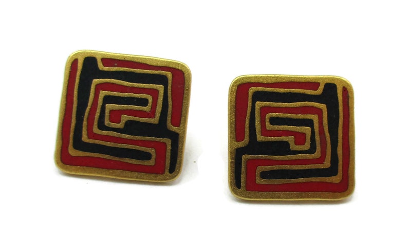Puede incluir: Un par de pendientes cuadrados con un borde dorado. Los pendientes presentan un dise&ntilde;o laber&iacute;ntico rojo y negro. Los pendientes est&aacute;n sobre un fondo blanco.
