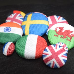 以下が含まれることがあります： インド、イタリア、ウェールズ、スウェーデン、イギリスなど、さまざまな国の旗が描かれた布製のボタンのコレクションです。