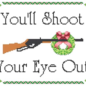Può includere: Un ricamo a punto croce bianco con un bordo rosso e verde. Il disegno presenta un fucile con una ghirlanda di Natale sul cannone e il testo "You'll Shoot Your Eye Out".