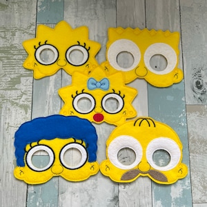 Puede incluir: Conjunto de cinco m&aacute;scaras de fieltro con personajes del programa de televisi&oacute;n animado Los Simpson. Las m&aacute;scaras son amarillas con ojos y bocas blancas. Los personajes incluyen a Homero, Marge, Bart, Lisa y Maggie.