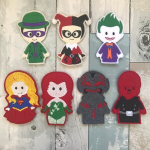 May include: Set of ten felt finger puppets featuring characters from popular comic books. The puppets are colorful and detailed, with recognizable features like Harley Quinn's jester hat and The Joker's green hair.
