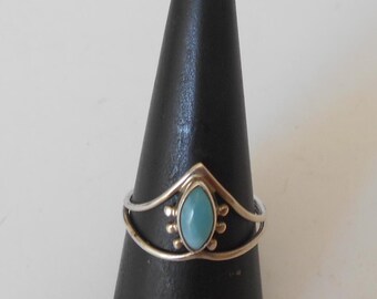 May include: A silver ring with a light blue gemstone set in a pointed crown design.