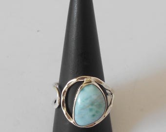 Puede incluir: Un anillo de plata con una piedra preciosa azul claro engastada en un diseño delicado y calado.
