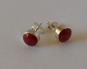 May include: A pair of silver stud earrings with red round gemstones.
