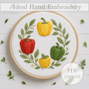 May include: Hand-embroidered hoop art featuring a design of four bell peppers in red, yellow, and green. The peppers are surrounded by green leaves and small white flowers. The text "Ideal Hand Embroidery" is at the top.