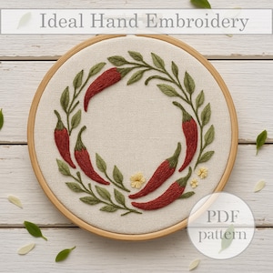 May include: Hand-embroidered design featuring a wreath of red chili peppers and green leaves on a cream-colored fabric, set within a wooden embroidery hoop. The text "Ideal Hand Embroidery" is at the top, and "PDF pattern" is in the lower right.