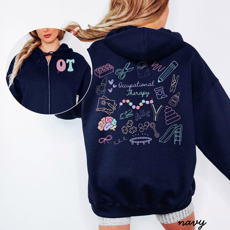 May include: Navy blue zip-up hoodie with the letters "OT" in pink and teal on the chest. The back features colorful line art illustrations related to occupational therapy, including scissors, a brain, and a slide. The word "navy" is at the bottom.