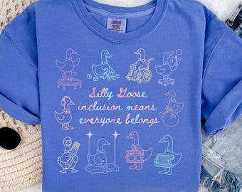 May include: A blue sweatshirt with the words "Silly Goose inclusion means everyone belongs" and illustrations of geese in various activities. The sweatshirt is a solid blue color with a Comfort Colors tag.