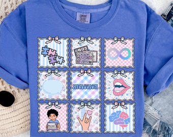 May include: A blue sweatshirt with a grid of colorful squares, each with a unique graphic. The graphics include puzzle pieces, an infinity symbol, and the word "INCLUSION". The sweatshirt has the text "flo blue" at the bottom.