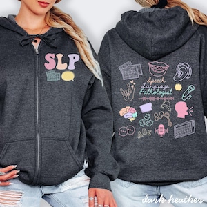 May include: Dark heather gray zip-up hoodie with the letters "SLP" in pastel colors on the front. The back features speech pathology-related graphics and the words "Speech Language Pathologist".
