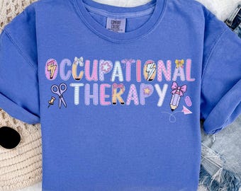 May include: A blue sweatshirt with the words "OCCUPATIONAL THERAPY" in a colorful, playful design. The design includes scissors, a pencil, and other related graphics. The sweatshirt is a Comfort Colors brand.