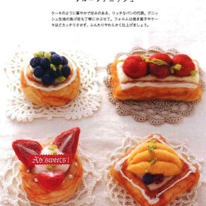 Peut inclure: Quatre pâtisseries miniatures en feutre avec différentes garnitures de fruits. Les pâtisseries sont sur des napperons blancs et un fond blanc. Les pâtisseries sont décorées de fruits en feutre, notamment des myrtilles, des fraises et de la mangue.