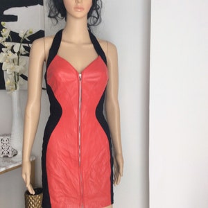 Puede incluir: Un vestido halter de cuero rojo y negro con cierre de cremallera en la parte delantera. El vestido es ajustado y tiene una falda corta.