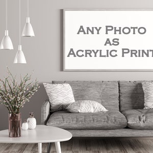 May include: A gray couch with three throw pillows, a white coffee table, and a vase with white flowers. A framed picture on the wall reads "ANY PHOTO AS ACRYLIC PRINT".