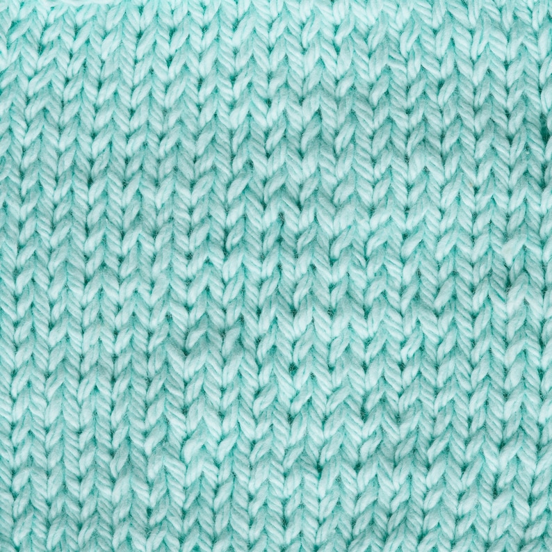 May include: Close-up of a light blue knitted fabric with a textured pattern. The fabric is soft and has a subtle sheen.