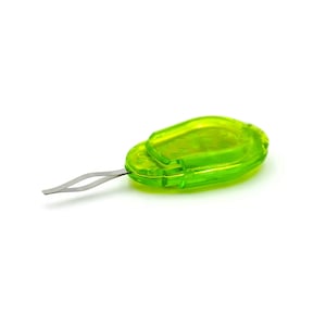 K&ouml;nnte beinhalten: Ein kleines, gr&uuml;nes Plastikwerkzeug mit einer Metallklinge. Das Werkzeug ist zum Entfernen von Flusen von Kleidung gedacht.