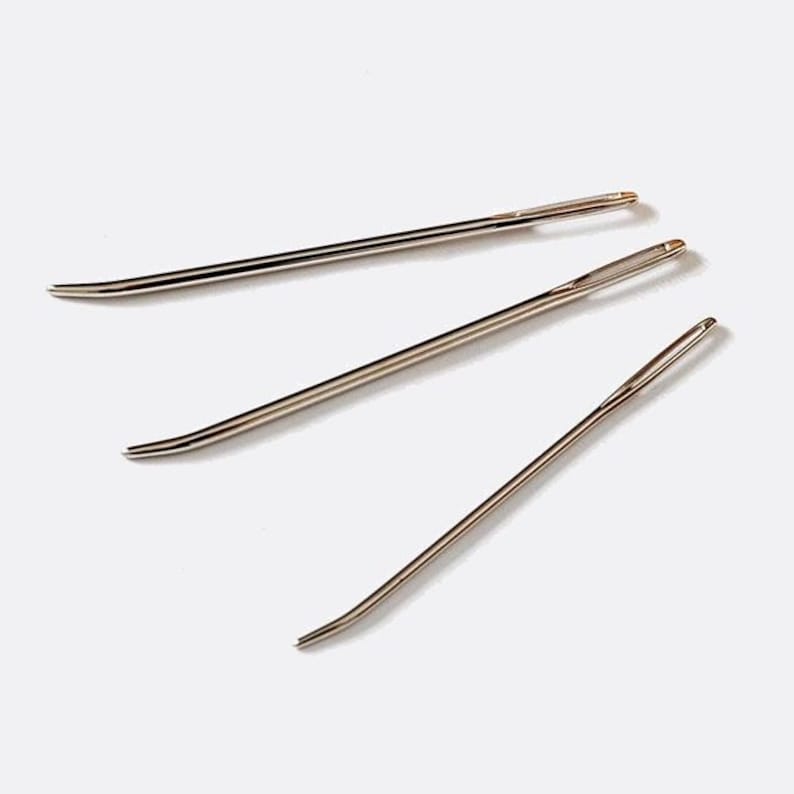 May include: Three silver sewing needles with pointed tips and eye holes for threading.
