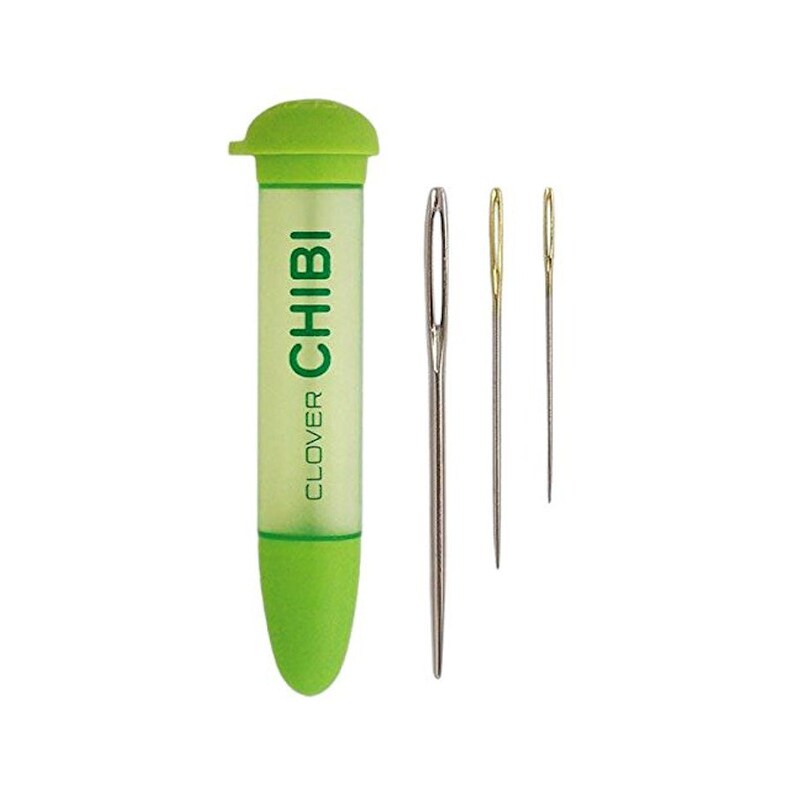 May include: A set of Clover Chibi sewing needles with a green and clear plastic tube. The tube has the word "CHIBI" in green. Three needles of varying sizes are next to the tube. One needle is silver, and two are gold.