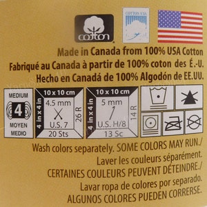 May include: A yellow label with the words "Made in Canada from 100% USA Cotton" and care instructions for washing and ironing. The label also includes the words "Medium", "Moyen", "Medio", "4", "26R", "14R", "U.S. 7", "20 Sts", "U.S. H/8", "13 Sc", "10 x 10 cm", "4.5 mm", "5 mm", and a graphic of a cotton boll.