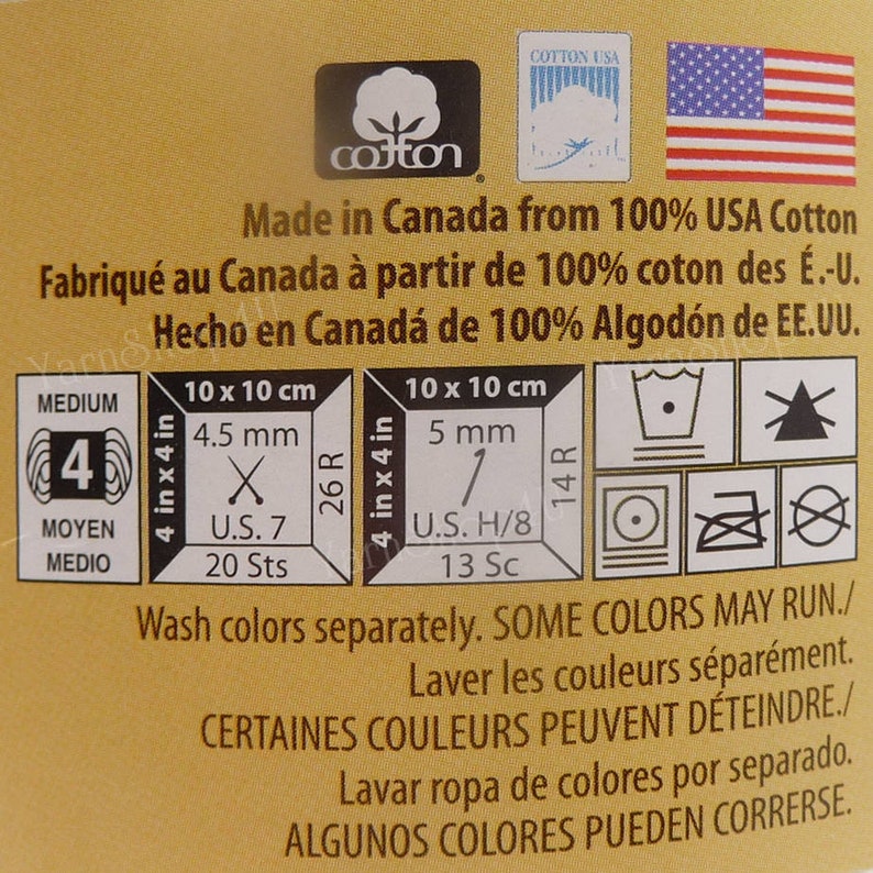 May include: A yellow label with the words "Made in Canada from 100% USA Cotton" and care instructions for washing and ironing. The label also includes the words "Medium", "Moyen", "Medio", "4", "26R", "14R", "U.S. 7", "20 Sts", "U.S. H/8", "13 Sc", "10 x 10 cm", "4.5 mm", "5 mm", and a graphic of a cotton boll.