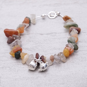 Peut inclure: Un bracelet à breloques en argent avec un charme théière et tasse. Le bracelet est fait avec une variété de pierres naturelles, y compris du quartz clair, de la cornaline et du jaspe.