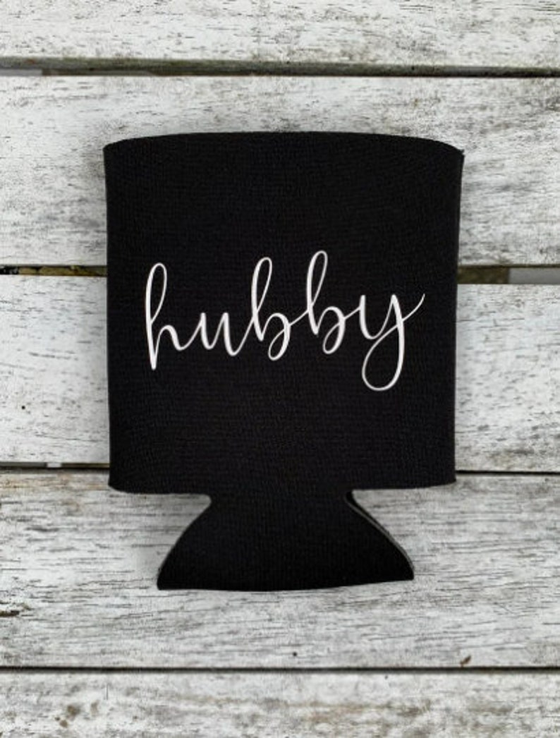 Puede incluir: Enfriador de latas de neopreno negro con la palabra "hubby" escrita en letra cursiva blanca.