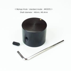 以下が含まれることがあります： 黒色のMpingoノブ、標準モデルMK3225、シャフト直径6mmと6.4mm。画像にはノブ、小さなネジ、銀色の六角レンチが写っています。ノブの上部には小さな金の点があります。