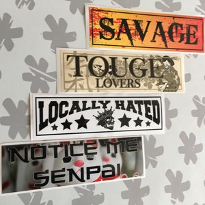 Op de afbeelding: Vier stickers met verschillende ontwerpen. De bovenste sticker is geel met rode en zwarte tekst die "SAVAGE" zegt. De tweede sticker is beige met zwarte tekst die "TOUGE LOVERS" zegt en een zwart-witte illustratie van een persoon. De derde sticker is wit met zwarte tekst die "LOCALLY HATRED" zegt en een zwart-witte illustratie van een schedel met een kroon. De onderste sticker is wit met zwarte tekst die "NOTICE ME SENPAI" zegt en een wazig beeld van een knuffeldier.
