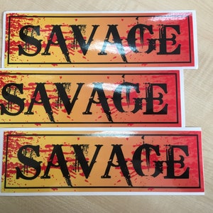 Op de afbeelding: Drie rechthoekige stickers met een gele en rode gradi&euml;nt achtergrond. De stickers hebben een zwarte rand en het woord "SAVAGE" in zwarte vetgedrukte letters.