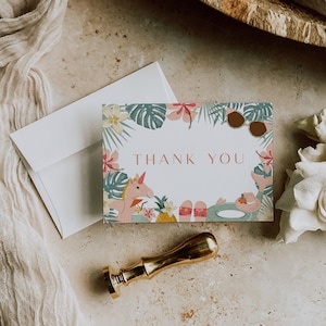 May include: A thank you card with a tropical theme featuring a unicorn wearing sunglasses and a floral border. The text "THANK YOU" is printed in a light brown font.
