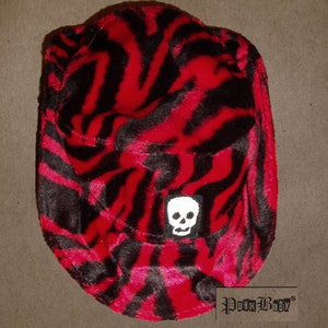 May include: A red and black zebra print bucket hat with a white skull graphic and the text "Punk Baby" on the bottom.