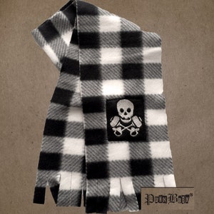 Puede incluir: Bufanda de franela a cuadros en blanco y negro con un parche de calavera y huesos cruzados y el texto "Punk Baby" en la esquina inferior derecha.