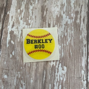 May include: Yellow softball sticker with red stitching and the text "BERKLEY #00" in black.