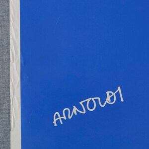 May include: A blue poster with white text that reads "Spar p&aring; energien - det er n&oslash;dvendigt". The poster has a white drop of water with a cross in it. The poster is signed "Anjou" in white.