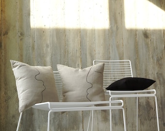 May include: Two white metal chairs with cushions. One chair has a black cushion and the other two have beige cushions with a black line drawing of a face on each.
