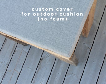 May include: A gray fabric cushion cover for outdoor furniture. The cover is on a wooden bench with the text "custom cover for outdoor cushion (no foam)" printed on it.