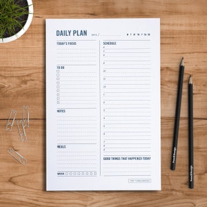 May include: A black and white daily planner with the words "DAILY PLAN" at the top. The planner has sections for "TODAY'S FOCUS", "SCHEDULE", "TO DO", "NOTES", "MEALS", "WATER", and "GOOD THINGS THAT HAPPENED TODAY".