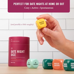 May include: A selection of date night dice featuring activity prompts. The image displays a yellow die with "WHIPPED CREAM" printed on it, alongside other dice with prompts such as "GO BOWLING" and "ESCAPE ROOM". A cylindrical container labelled "DATE NIGHT DICE" is also present.