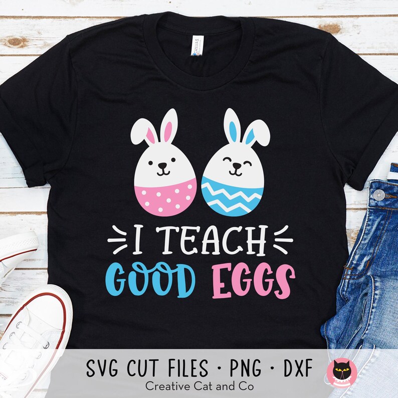 May include: Black t-shirt featuring a graphic of two Easter eggs, one pink and one blue, with bunny ears. The text "I Teach Good Eggs" is printed below the eggs.