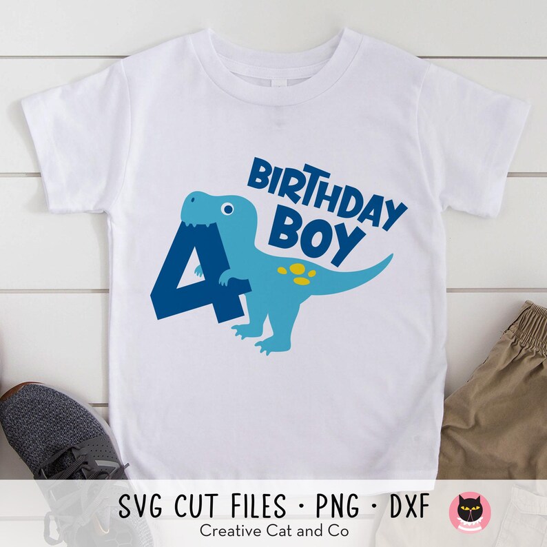May include: A white t-shirt with a blue dinosaur holding a blue number four. The text "Birthday Boy" is above the dinosaur.
