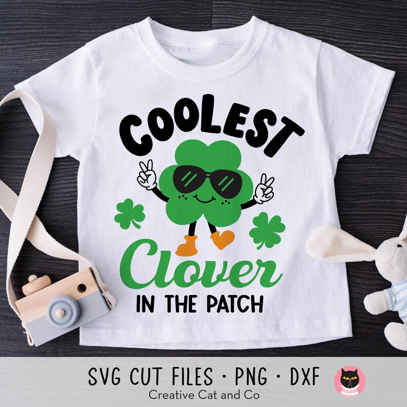 May include: White t-shirt with a green clover wearing sunglasses and the text "Coolest Clover in the Patch".