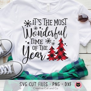 Könnte beinhalten: Weißes T-Shirt mit schwarzem Text, der "Es ist die schönste Zeit des Jahres" lautet, mit rot-schwarzen karierten Weihnachtsbäumen.