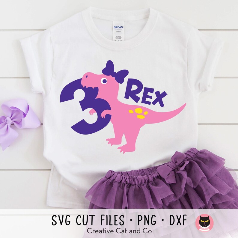 Pu&ograve; includere: Una maglietta bianca con un dinosauro rosa che indossa un fiocco viola e tiene un numero 3 viola. Il dinosauro ha macchie gialle e il testo "Rex" &egrave; sopra il dinosauro.  SVG CUT FILES - PNG - DXF Creative Cat and Co.