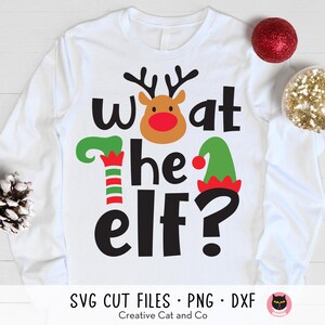 May include: White long-sleeve shirt with a red-nosed reindeer and elf hat graphic. The text "What the elf?" is printed in black.