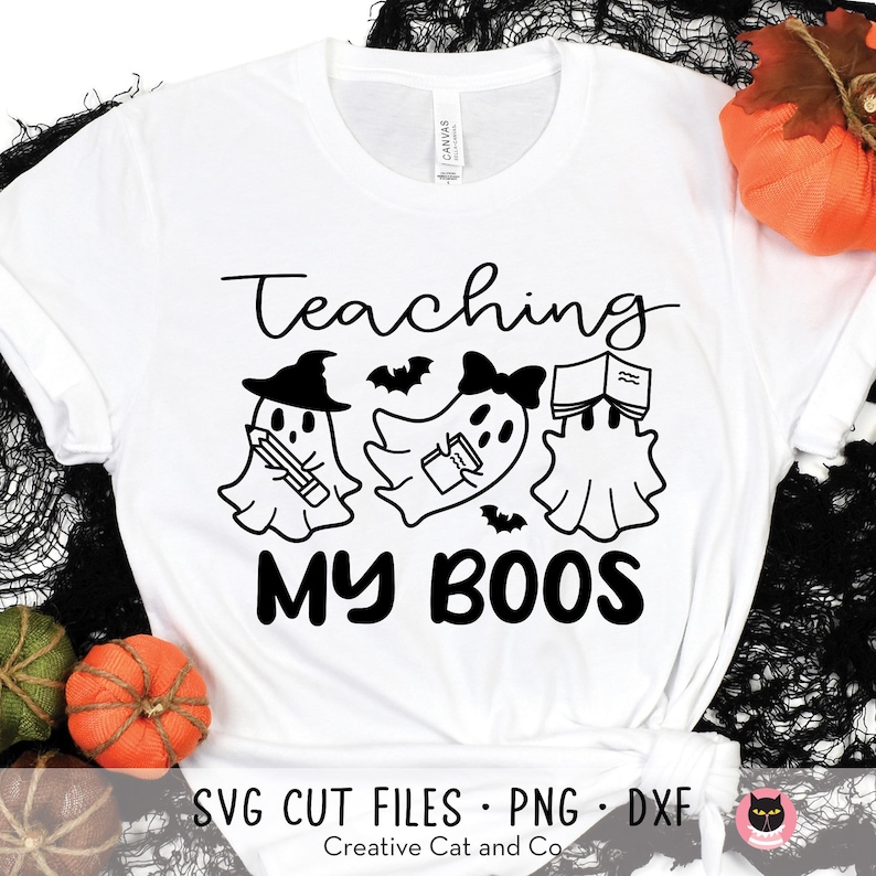 May include: White t-shirt with black text that reads "Teaching My Boos". The text is surrounded by three ghosts holding books and pencils.