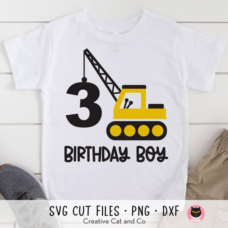 May include: A white t-shirt with a yellow and black construction crane graphic and the number 3. The text "Birthday Boy" is below the crane.