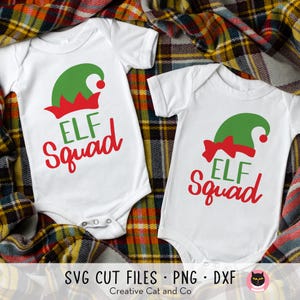 May include: Two white onesies with red and green elf hats and the text "Elf Squad" on them. The onesies are on a plaid fabric background.