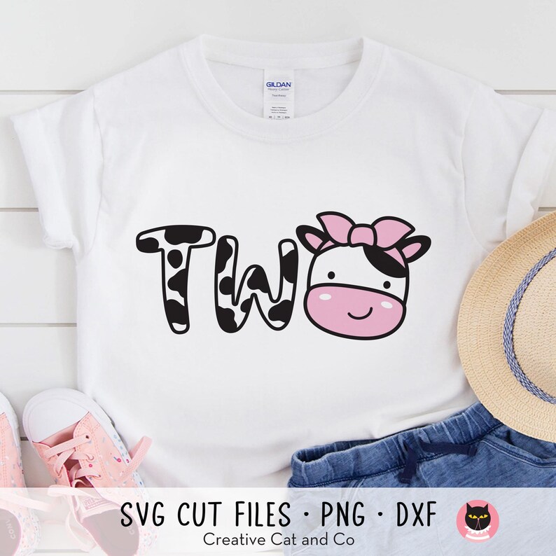 Może przedstawiać: Biały t-shirt z napisem "TWO" w czarno-białym wzorze krowy z r&oacute;żową i białą twarzą krowy z r&oacute;żową kokardką na g&oacute;rze. Tekst "SVG CUT FILES - PNG - DXF" znajduje się na dole obrazu.